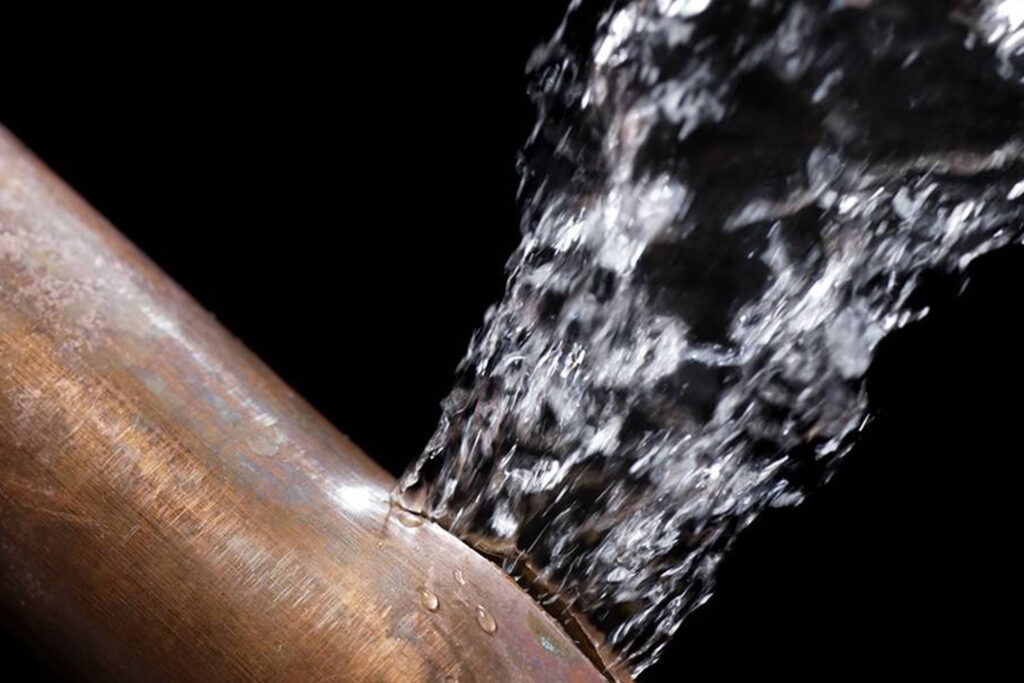 Close up of water bursting out of copper pipe