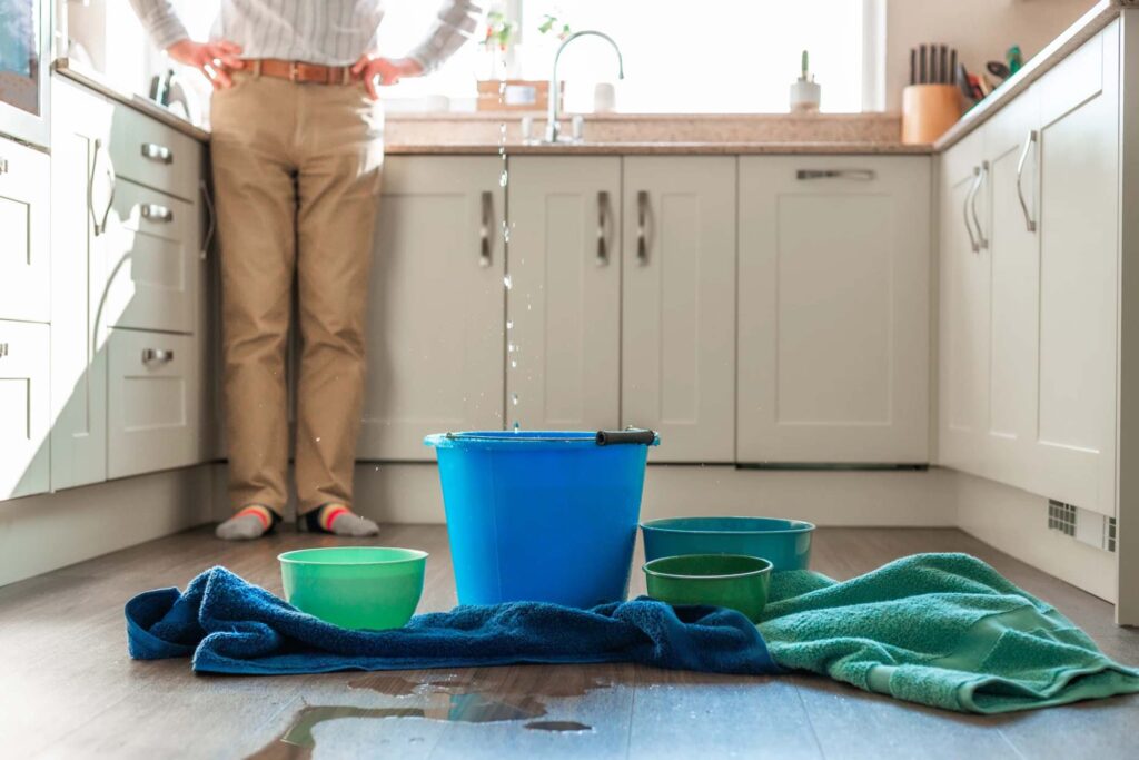 Puddle of water, buckets, and towels in middle of kitchen floor