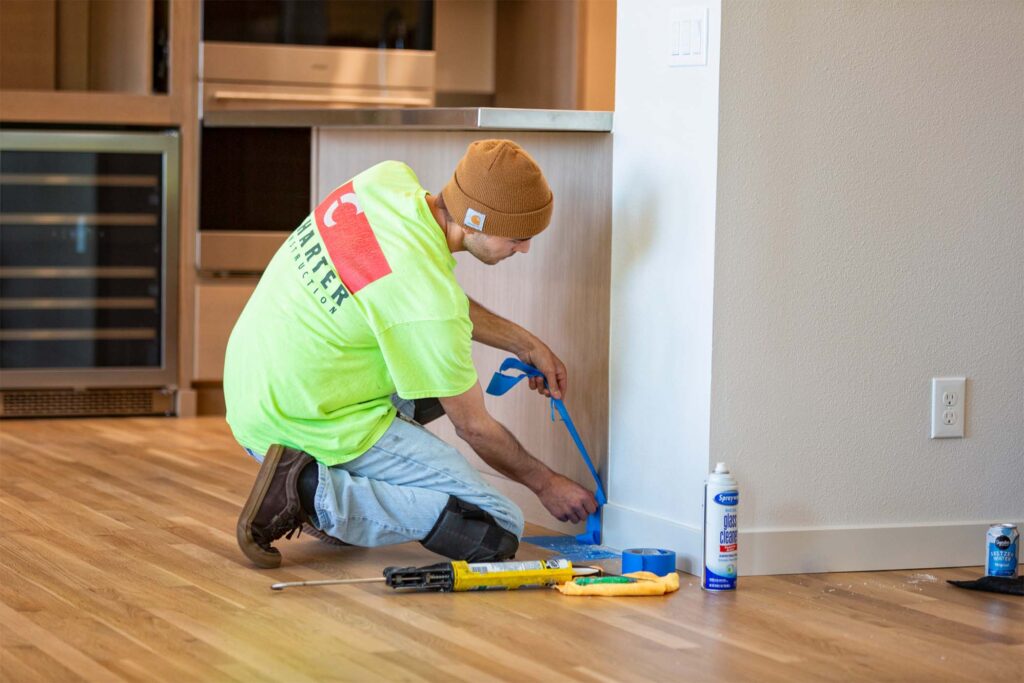 Construction worker tapping off kitchen cabinet for painting